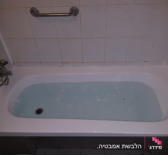 אמבטיה מלאה במים עם ידית אחיזה על הקיר